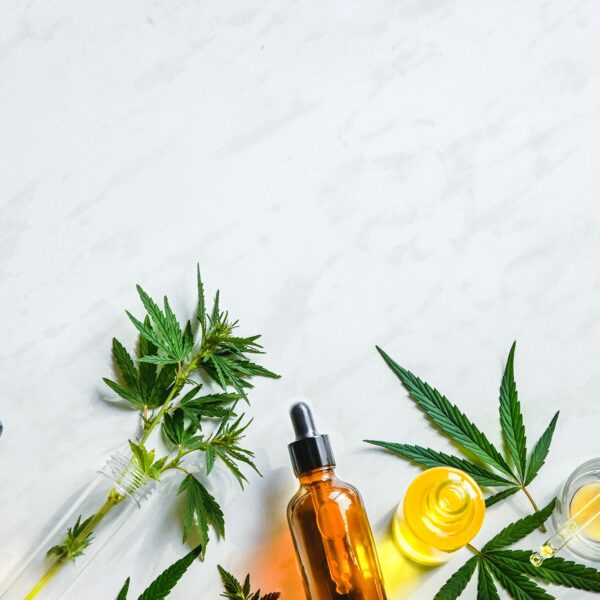 Various glass bottles with CBD oil, THC tincture hemp leaves on marble background Cosmetics CBD oil