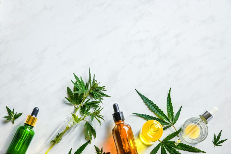Various glass bottles with CBD oil, THC tincture hemp leaves on marble background Cosmetics CBD oil