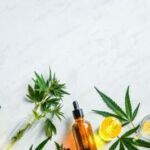 Various glass bottles with CBD oil, THC tincture hemp leaves on marble background Cosmetics CBD oil