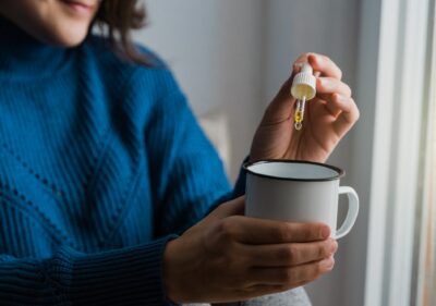 Woman taking Cannabis cbd oil inside tea cup - Alternative medicine, vitamins and supplements