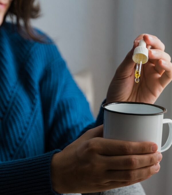 Woman taking Cannabis cbd oil inside tea cup - Alternative medicine, vitamins and supplements