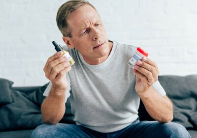 handsome man in t-shirt holding medical cannabis and cannabis oil