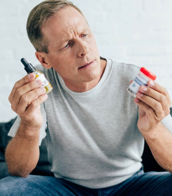 handsome man in t-shirt holding medical cannabis and cannabis oil